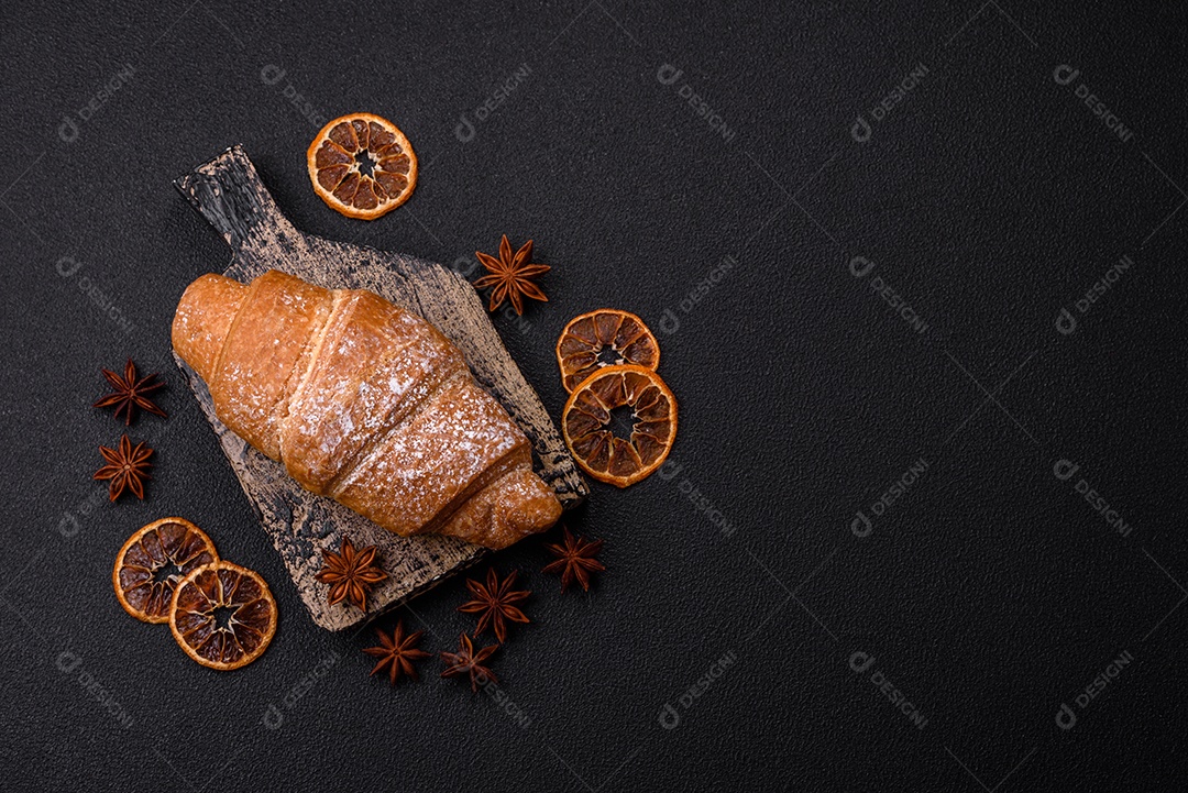 Delicioso croissant dourado crocante com recheio de chocolate sobre um fundo escuro de concreto