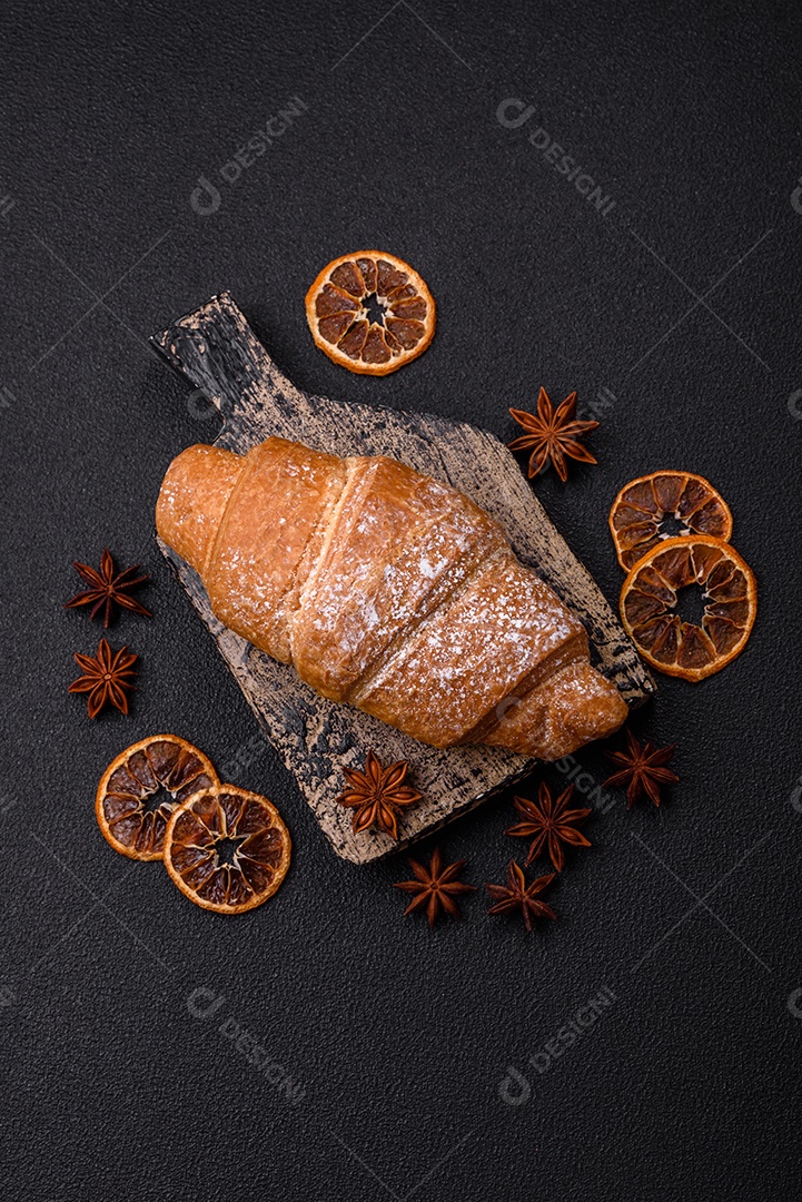 Delicioso croissant dourado crocante com recheio de chocolate sobre um fundo escuro de concreto