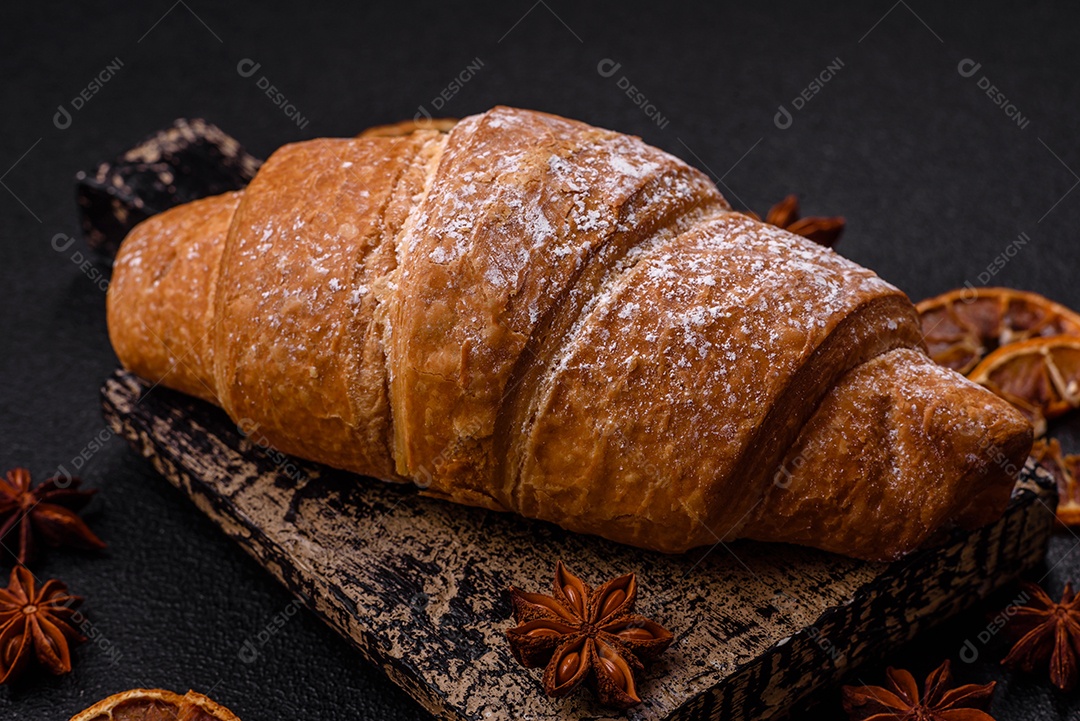 Delicioso croissant dourado crocante com recheio de chocolate sobre um fundo escuro de concreto