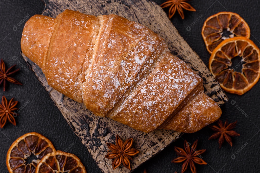 Delicioso croissant dourado crocante com recheio de chocolate sobre um fundo escuro de concreto