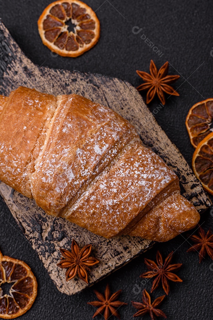 Delicioso croissant dourado crocante com recheio de chocolate sobre um fundo escuro de concreto