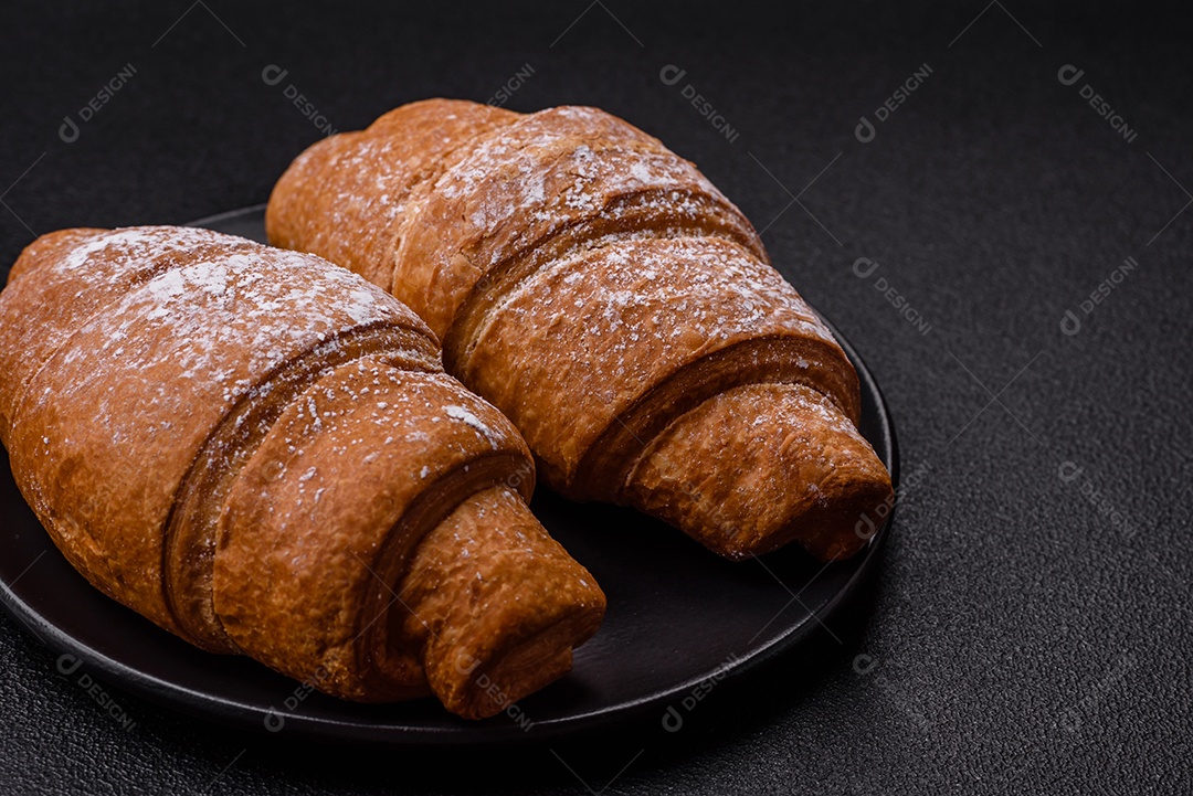 Delicioso croissant dourado crocante com recheio de chocolate sobre um fundo escuro de concreto