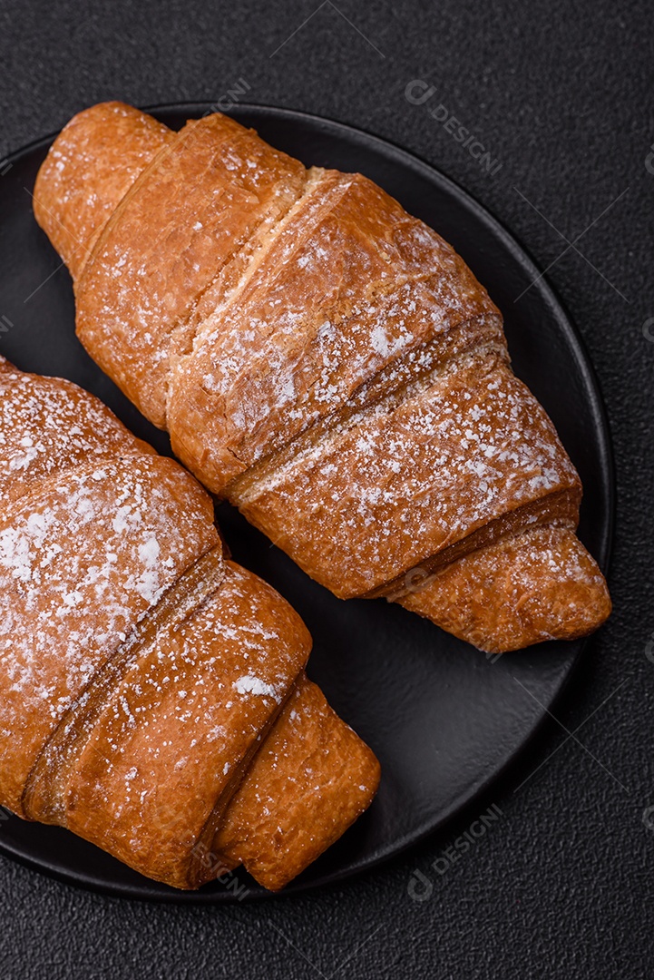 Delicioso croissant dourado crocante com recheio de chocolate sobre um fundo escuro de concreto