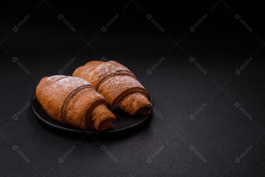 Delicioso croissant dourado crocante com recheio de chocolate sobre um fundo escuro de concreto
