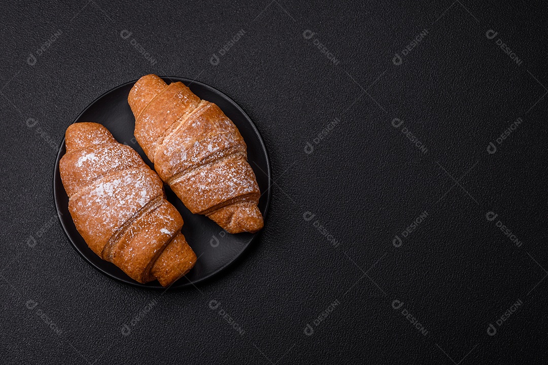 Delicioso croissant dourado crocante com recheio de chocolate sobre um fundo escuro de concreto
