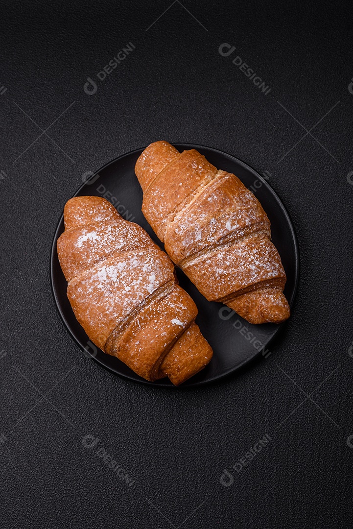 Delicioso croissant dourado crocante com recheio de chocolate sobre um fundo escuro de concreto