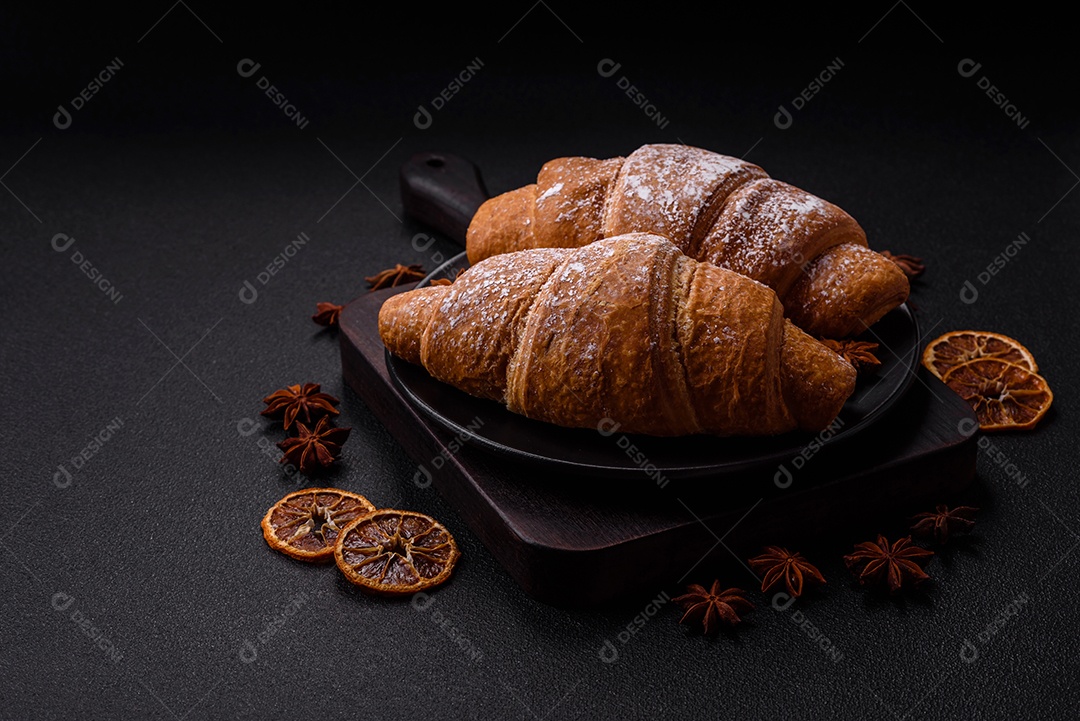 Delicioso croissant dourado crocante com recheio de chocolate sobre um fundo escuro de concreto