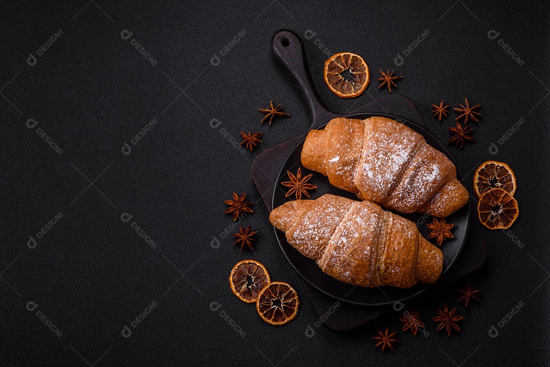 Delicioso croissant dourado crocante com recheio de chocolate sobre um fundo escuro de concreto