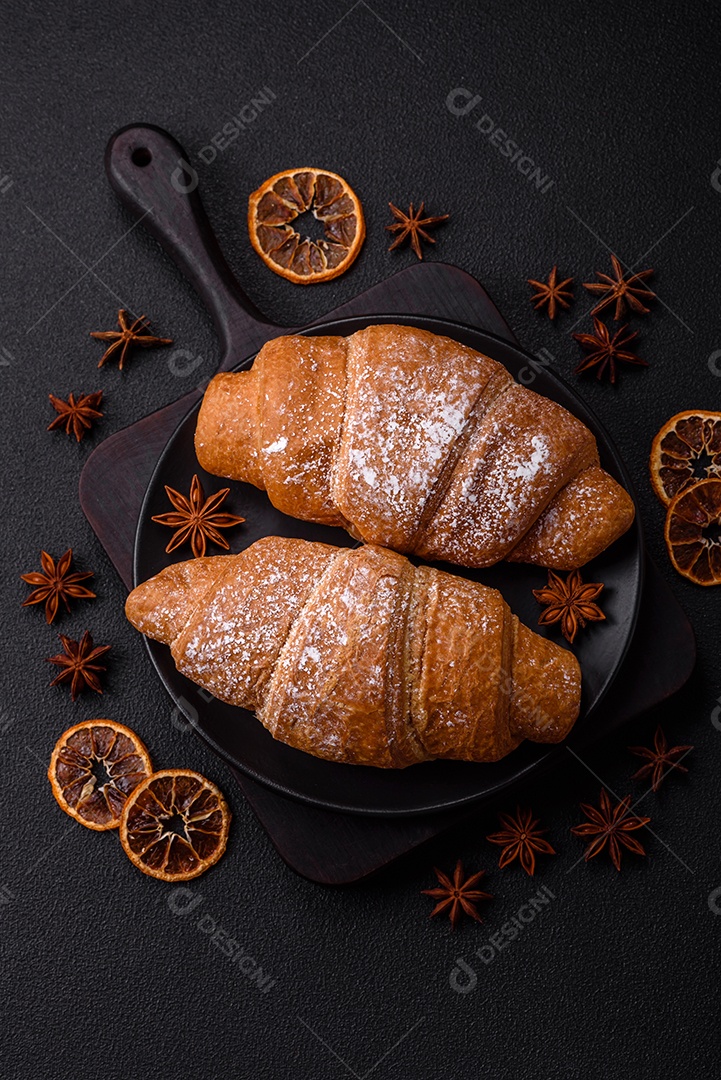 Delicioso croissant dourado crocante com recheio de chocolate sobre um fundo escuro de concreto