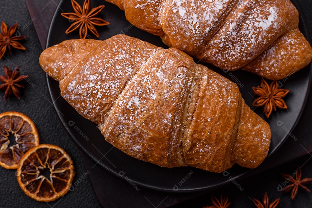 Delicioso croissant dourado crocante com recheio de chocolate sobre um fundo escuro de concreto