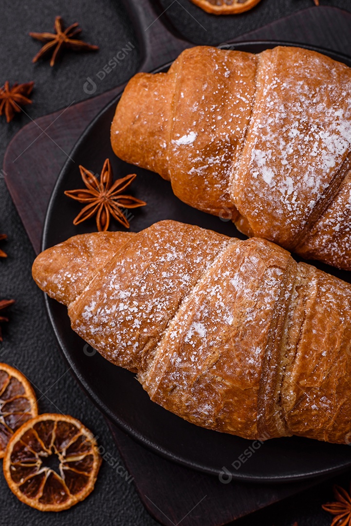 Delicioso croissant dourado crocante com recheio de chocolate sobre um fundo escuro de concreto