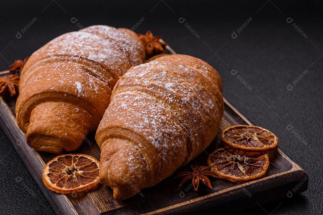 Delicioso croissant dourado crocante com recheio de chocolate sobre um fundo escuro de concreto
