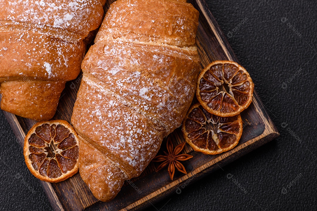 Delicioso croissant dourado crocante com recheio de chocolate sobre um fundo escuro de concreto