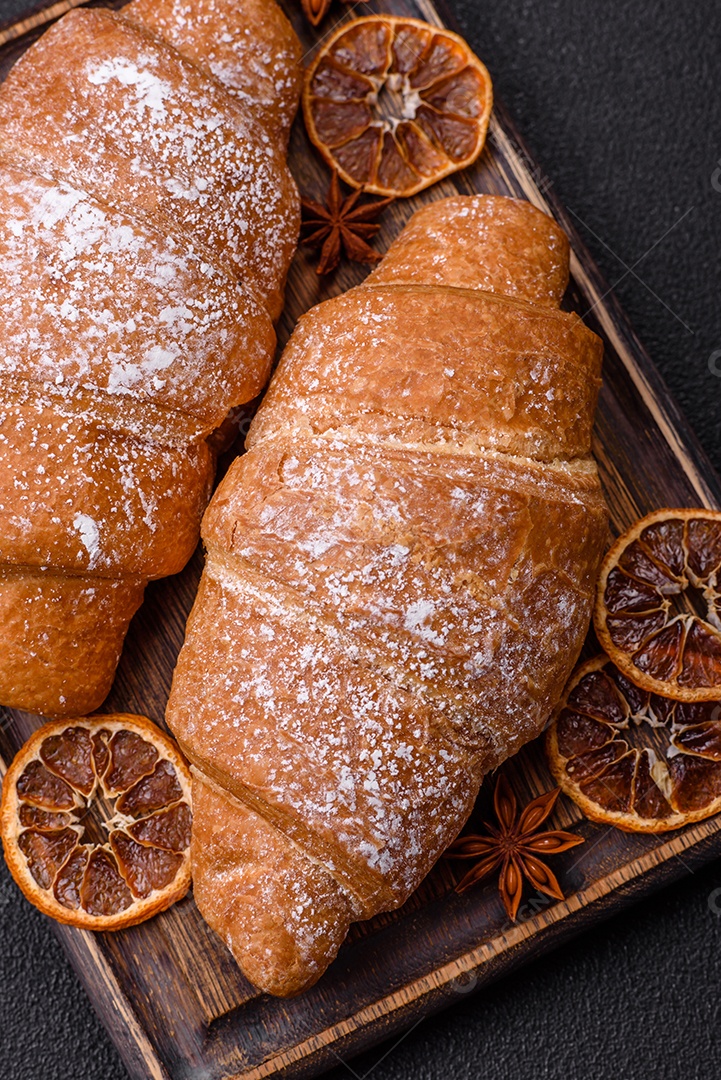 Delicioso croissant dourado crocante com recheio de chocolate sobre um fundo escuro de concreto