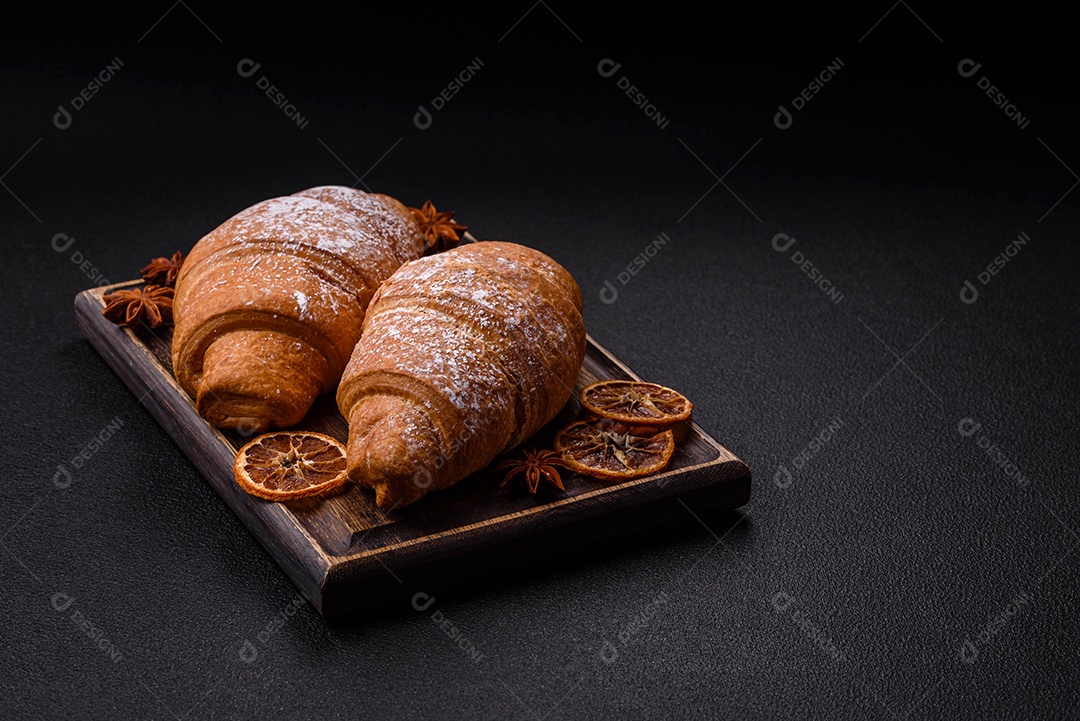 Delicioso croissant dourado crocante com recheio de chocolate sobre um fundo escuro de concreto