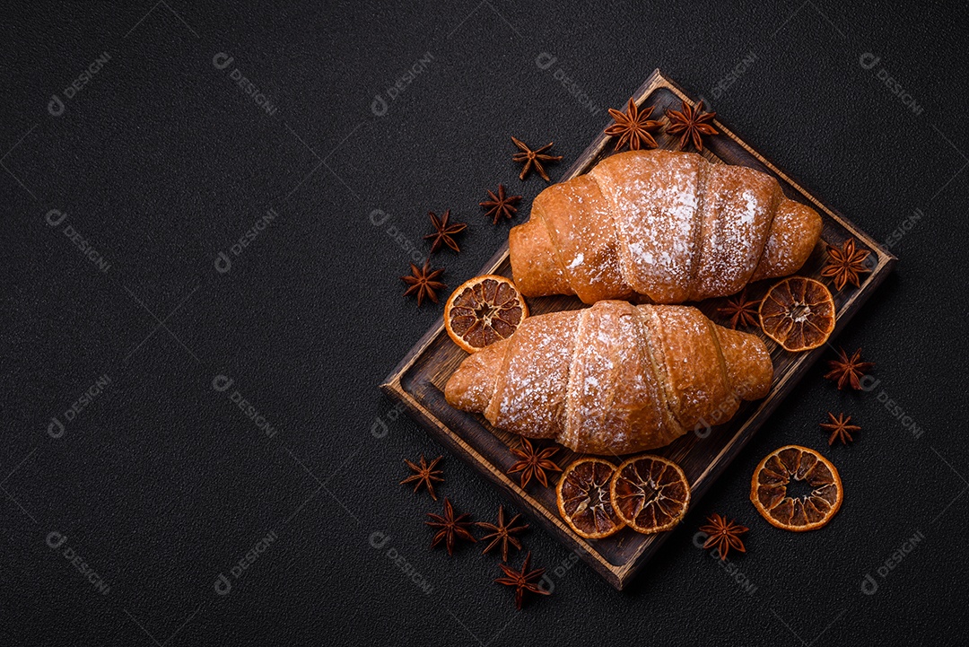 Delicioso croissant dourado crocante com recheio de chocolate sobre um fundo escuro de concreto
