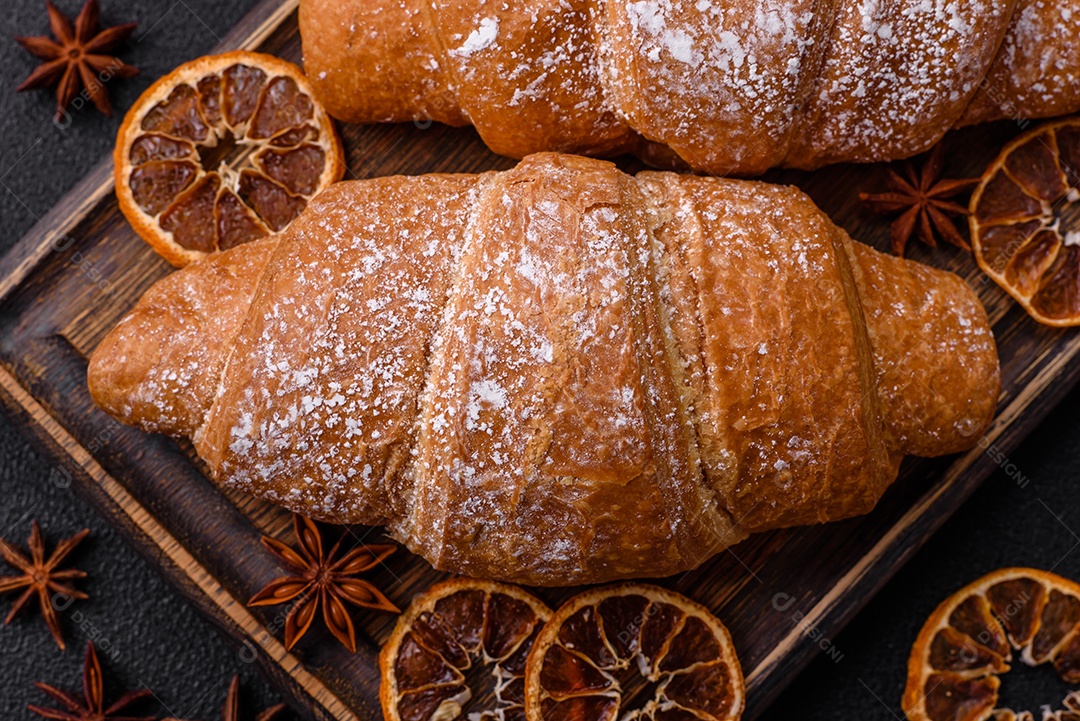 Delicioso croissant dourado crocante com recheio de chocolate sobre um fundo escuro de concreto