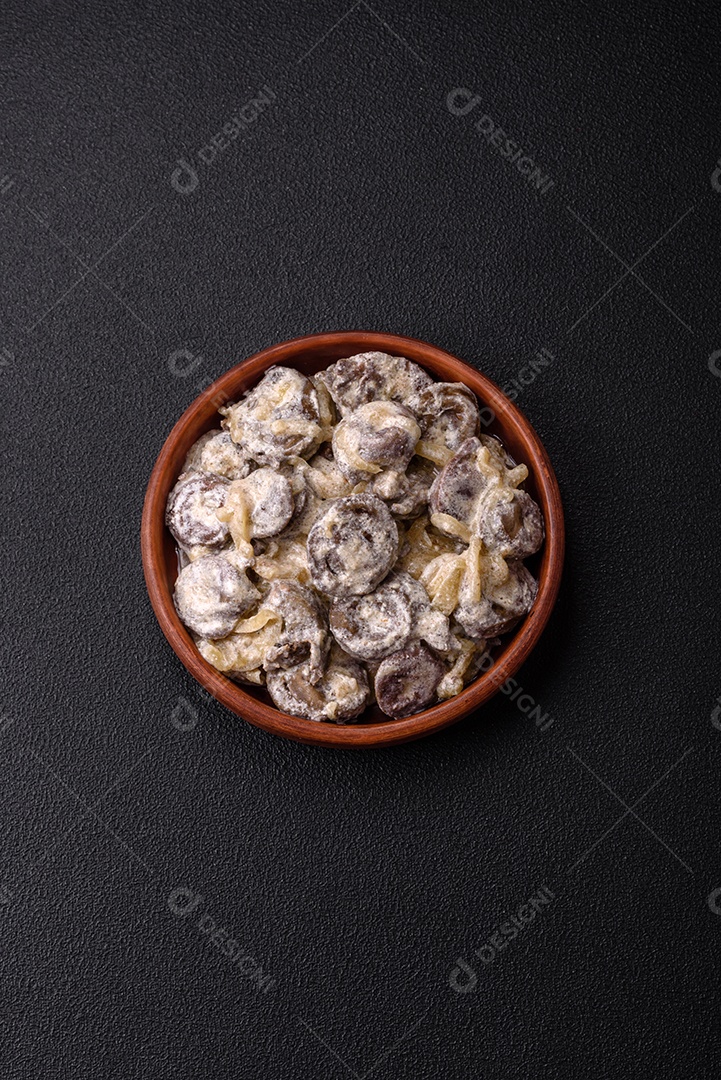 Corações de frango cozido cortados em fatias com cebola e molho cremoso com sal e especiarias sobre um fundo escuro de concreto