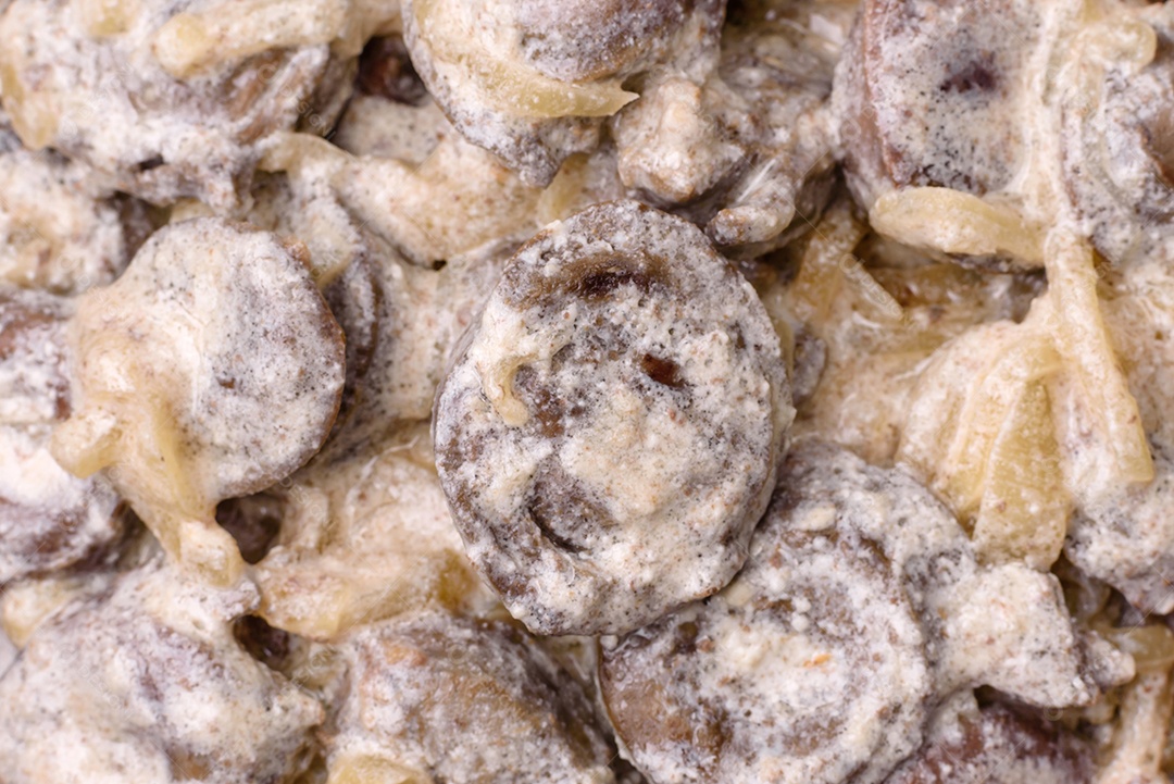 Corações de frango cozido cortados em fatias com cebola e molho cremoso com sal e especiarias sobre um fundo escuro de concreto