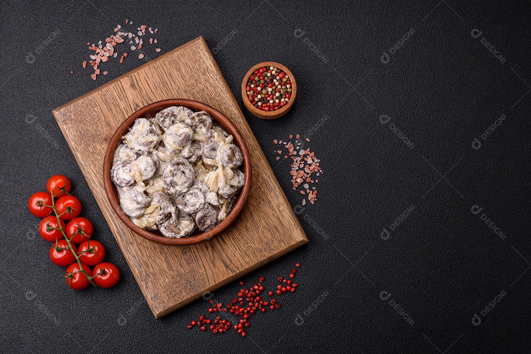 Corações de frango cozido cortados em fatias com cebola e molho cremoso com sal e especiarias sobre um fundo escuro de concreto