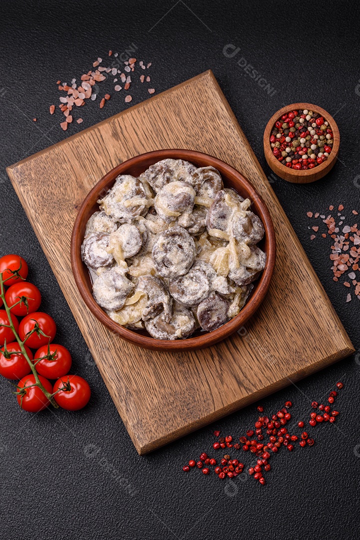 Corações de frango cozido cortados em fatias com cebola e molho cremoso com sal e especiarias sobre um fundo escuro de concreto