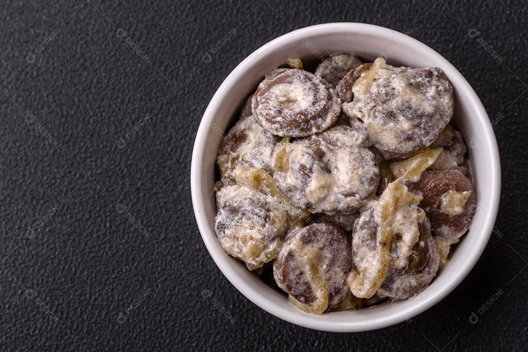 Corações de frango cozido cortados em fatias com cebola e molho cremoso com sal e especiarias sobre um fundo escuro de concreto