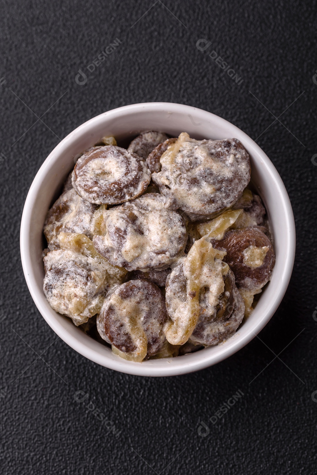 Corações de frango cozido cortados em fatias com cebola e molho cremoso com sal e especiarias sobre um fundo escuro de concreto