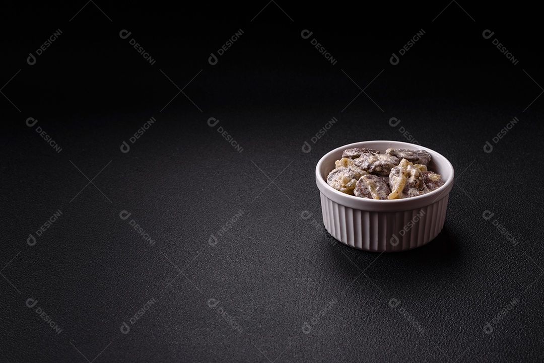 Corações de frango cozido cortados em fatias com cebola e molho cremoso com sal e especiarias sobre um fundo escuro de concreto