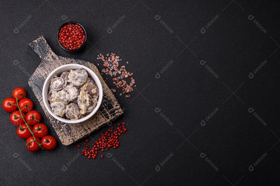 Corações de frango cozido cortados em fatias com cebola e molho cremoso com sal e especiarias sobre um fundo escuro de concreto