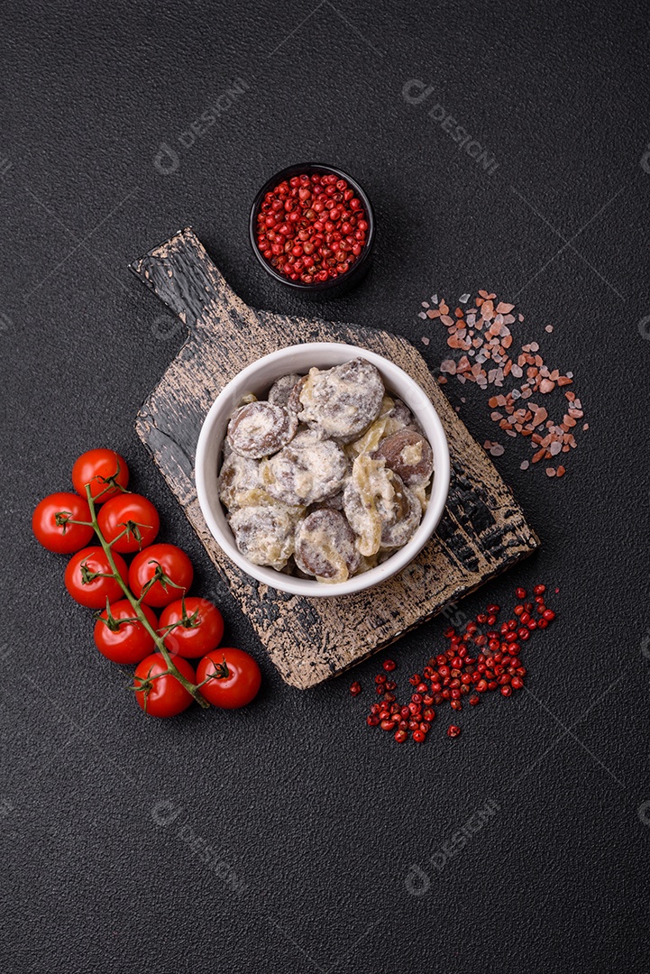 Corações de frango cozido cortados em fatias com cebola e molho cremoso com sal e especiarias sobre um fundo escuro de concreto