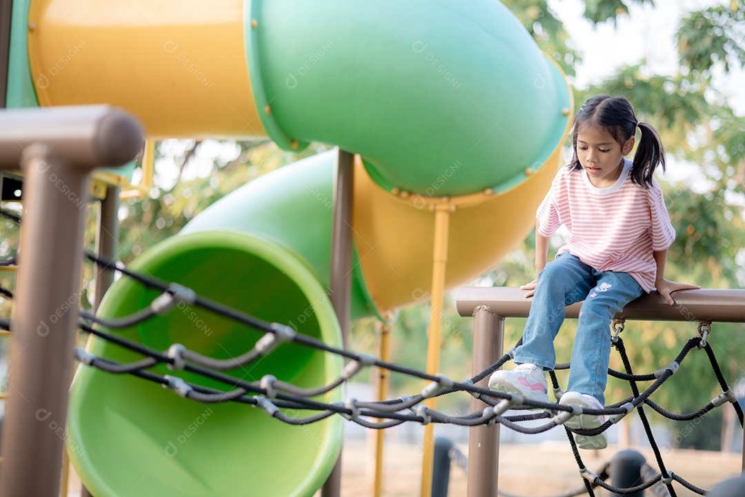 Uma menina sapeca brincando em rede de parquinho