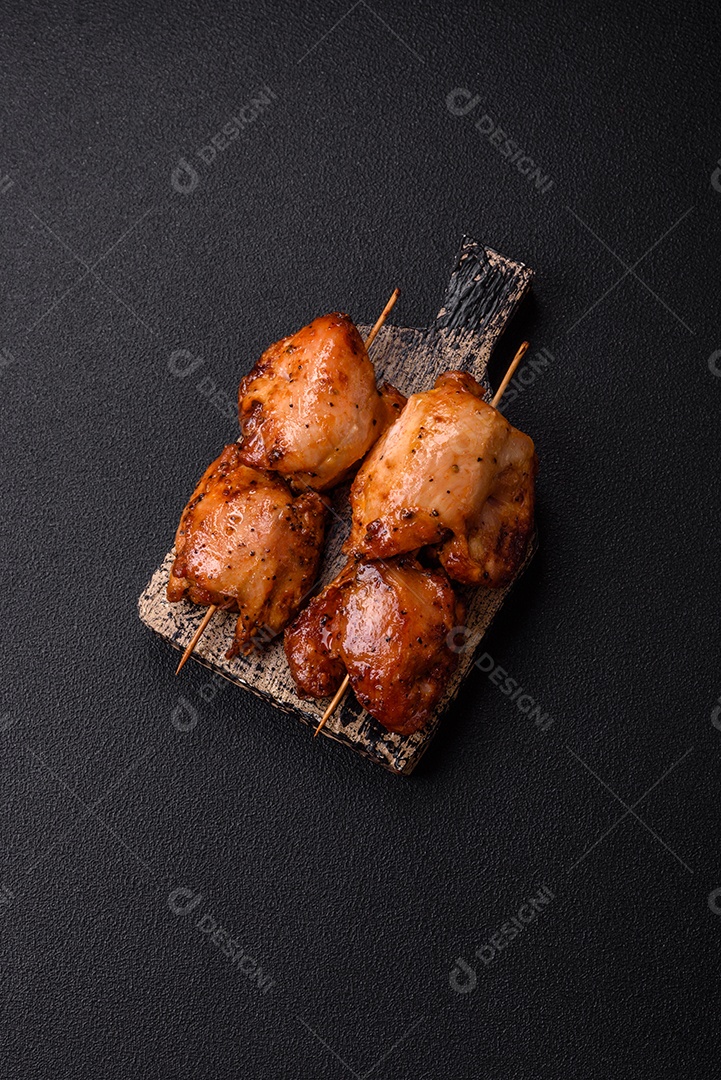 Kebab de frango suculento com sal, especiarias e ervas em um fundo escuro de concreto