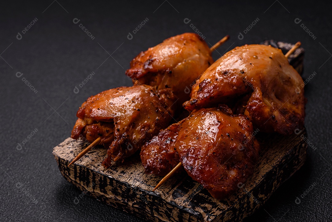 Kebab de frango suculento com sal, especiarias e ervas em um fundo escuro de concreto