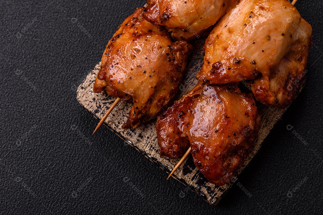Kebab de frango suculento com sal, especiarias e ervas em um fundo escuro de concreto