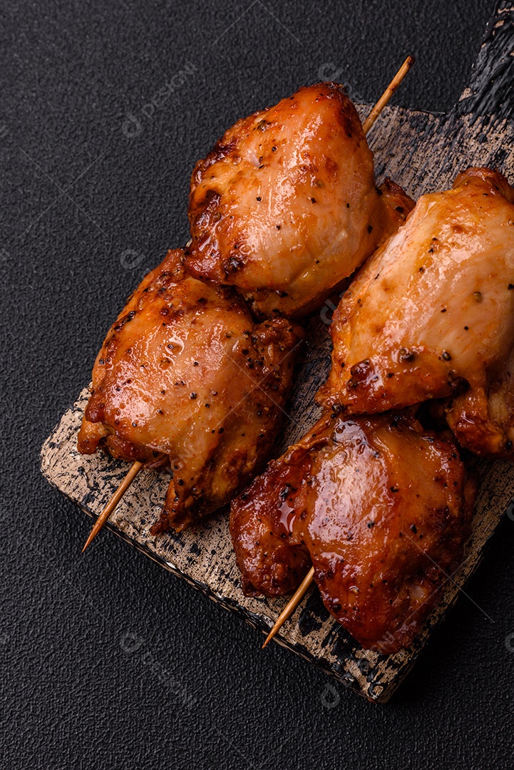 Kebab de frango suculento com sal, especiarias e ervas em um fundo escuro de concreto