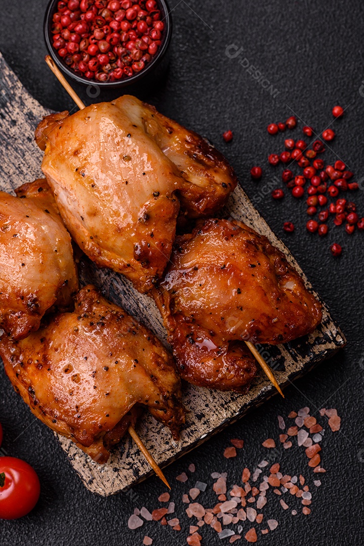 Kebab de frango suculento com sal, especiarias e ervas em um fundo escuro de concreto