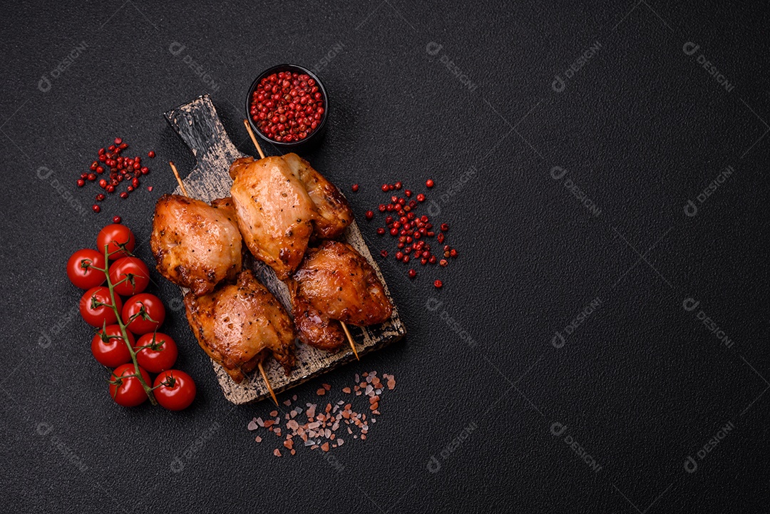 Kebab de frango suculento com sal, especiarias e ervas em um fundo escuro de concreto