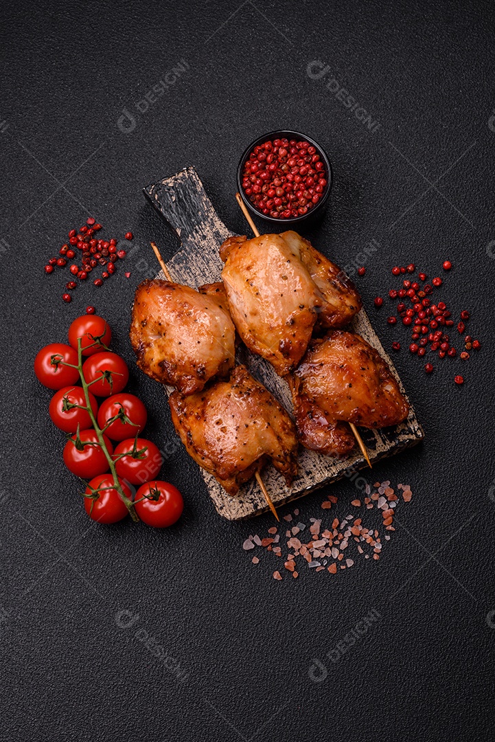 Kebab de frango suculento com sal, especiarias e ervas em um fundo escuro de concreto