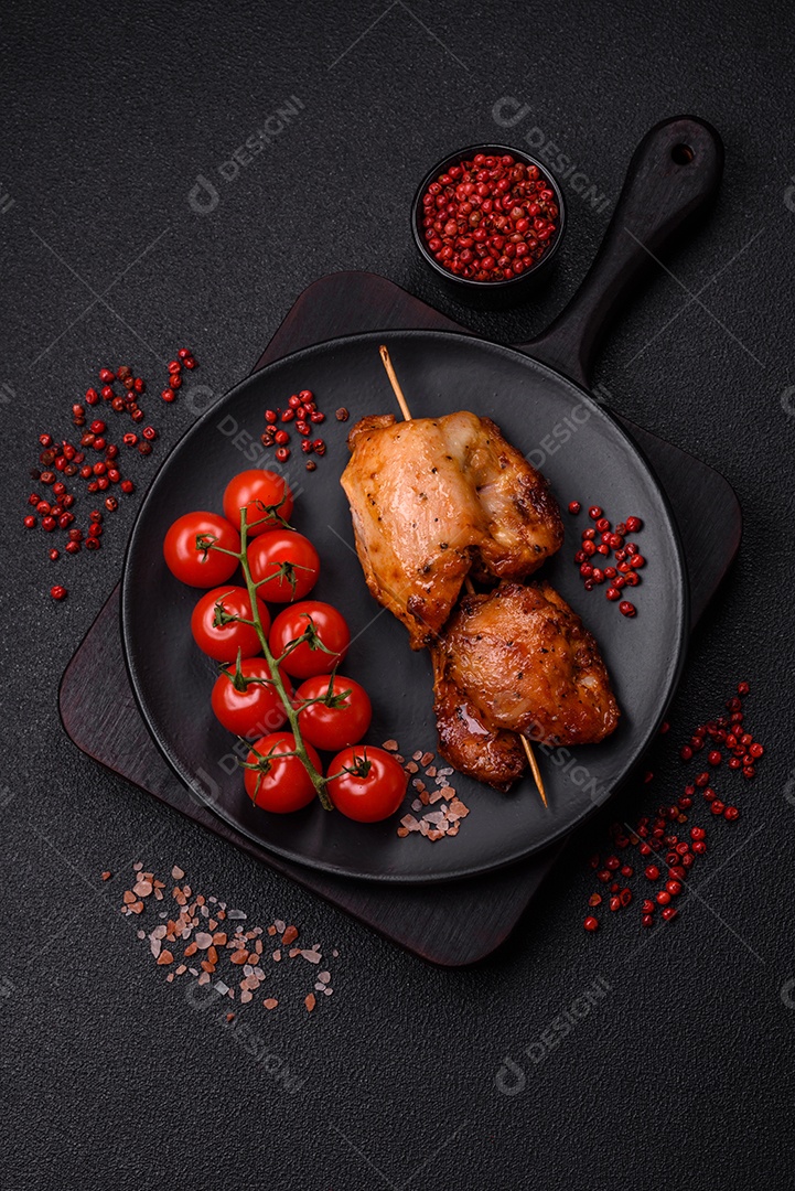 Kebab de frango suculento com sal, especiarias e ervas em um fundo escuro de concreto