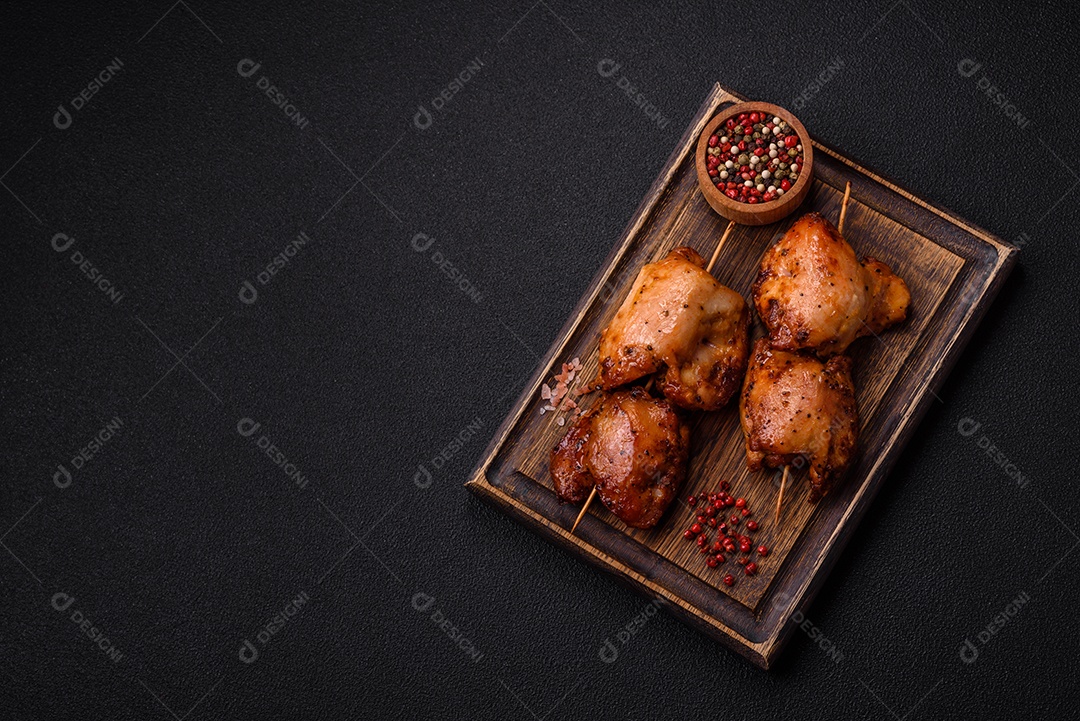 Kebab de frango suculento com sal, especiarias e ervas em um fundo escuro de concreto