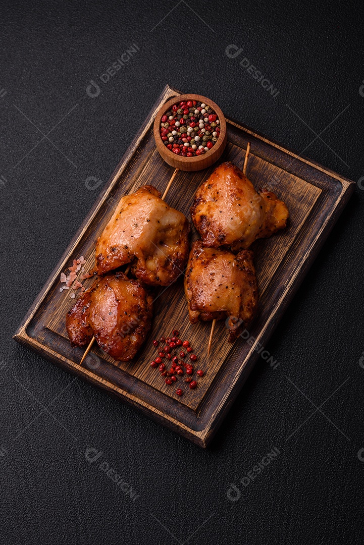 Kebab de frango suculento com sal, especiarias e ervas em um fundo escuro de concreto