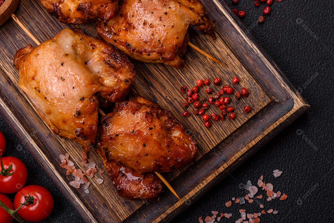 Kebab de frango suculento com sal, especiarias e ervas em um fundo escuro de concreto
