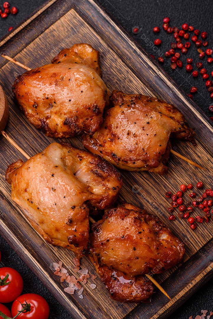 Kebab de frango suculento com sal, especiarias e ervas em um fundo escuro de concreto