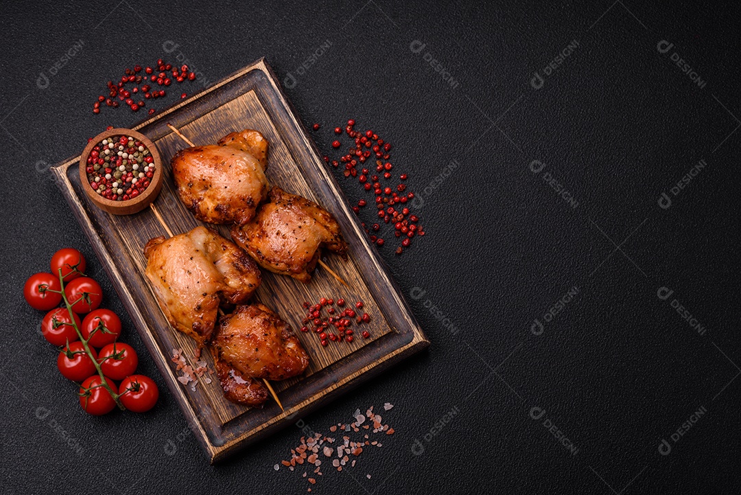 Kebab de frango suculento com sal, especiarias e ervas em um fundo escuro de concreto