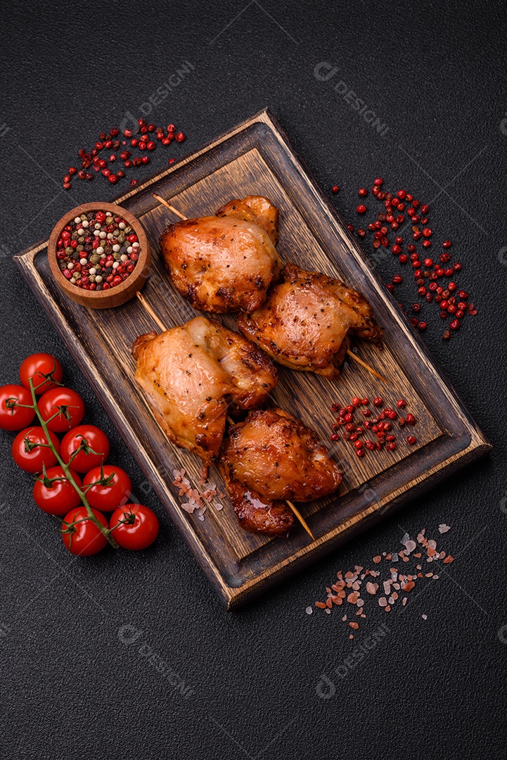 Kebab de frango suculento com sal, especiarias e ervas em um fundo escuro de concreto