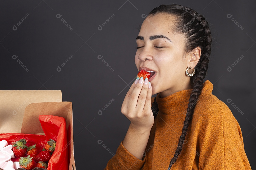 Mulher comendo morango de cesta de chocolate presente de dia dos namorados
