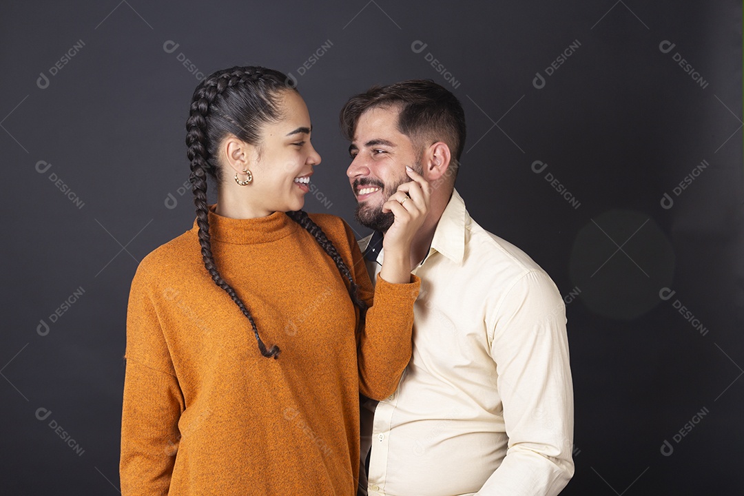 Mulher pegando em rosto de seu par para fotografia sobre fundo escuro