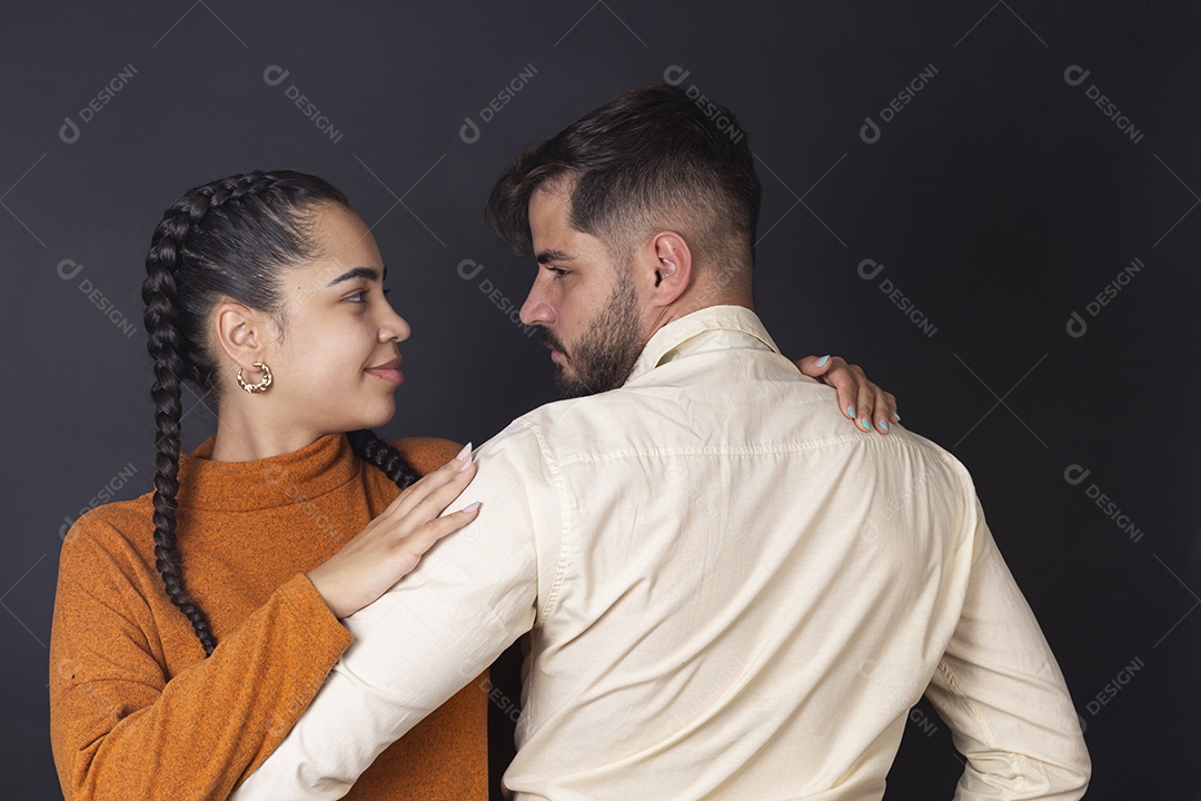 Casal jovem sorridentes se olhando em fundo escuro