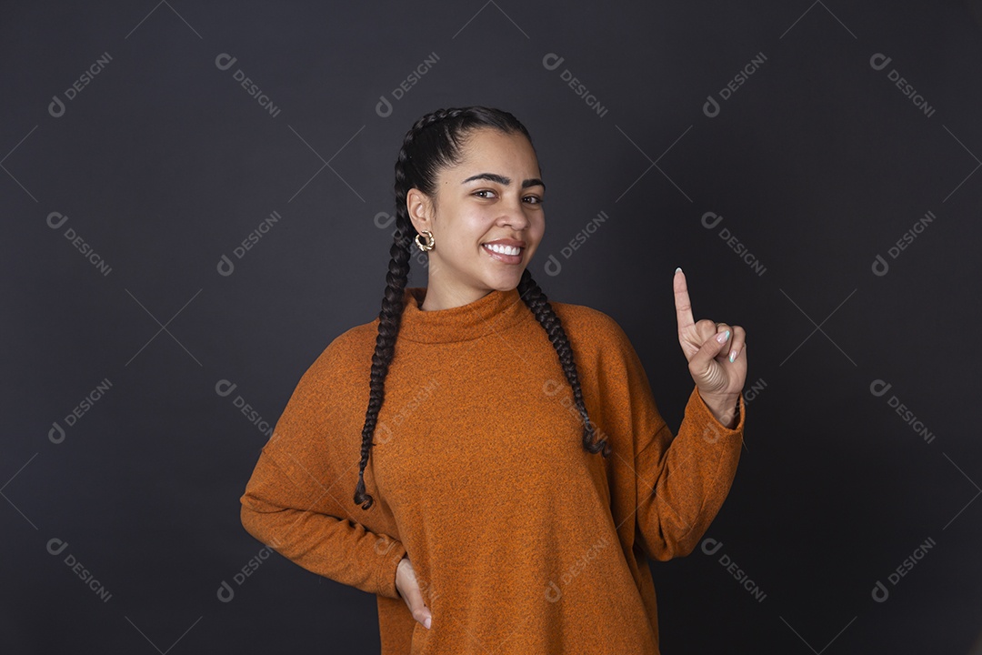 Mulher sorrindo com gesto de um sobre fundo escuro