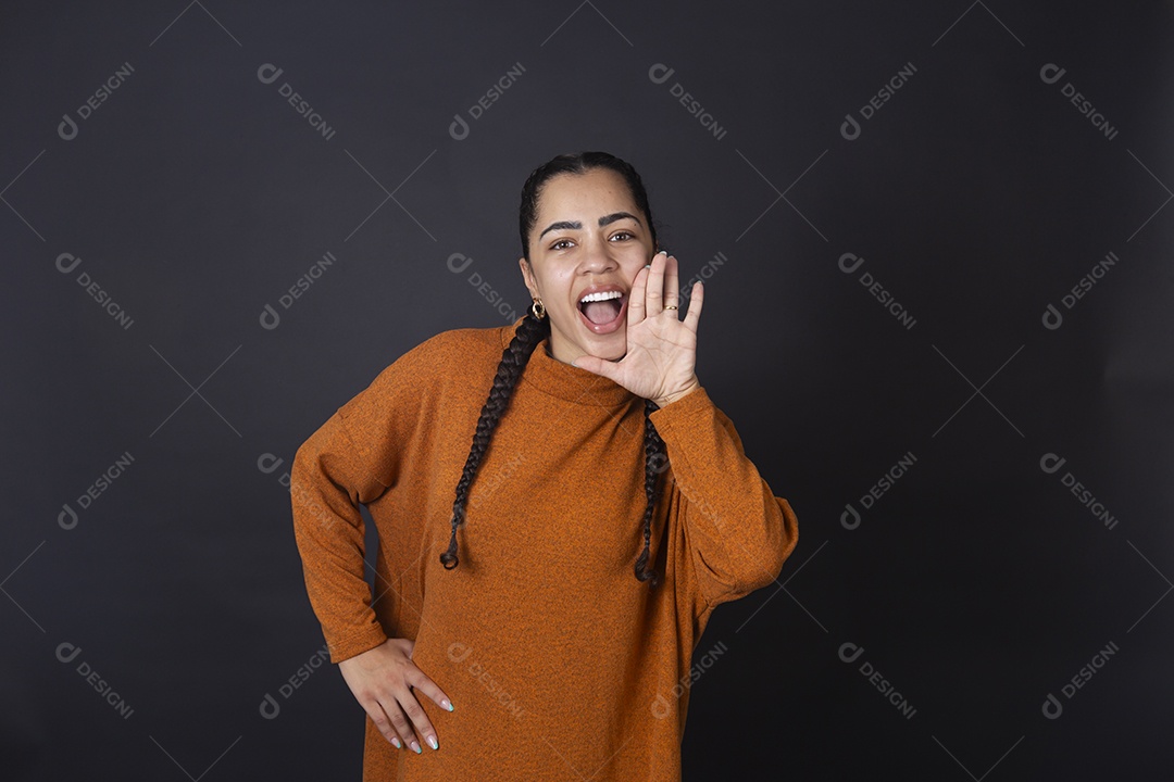 Mulher  com pose de mão na boca gritando sobre fundo escuro